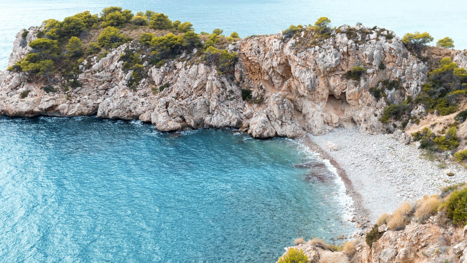 Cala turquesa y promontorio de pinos en la costa de Jávea